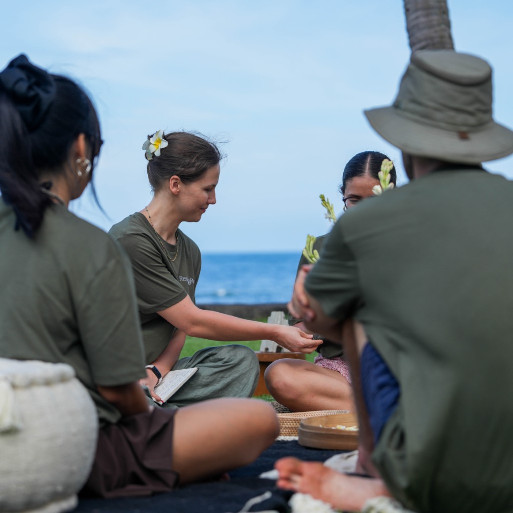 A small group seated in a circle at a coastal memorial gathering